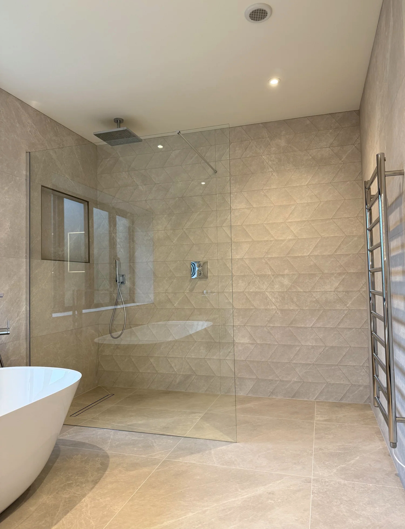 Chevron-tiled walk-in shower with freestanding bath and chrome towel rail — bathroom renovation Basingstoke